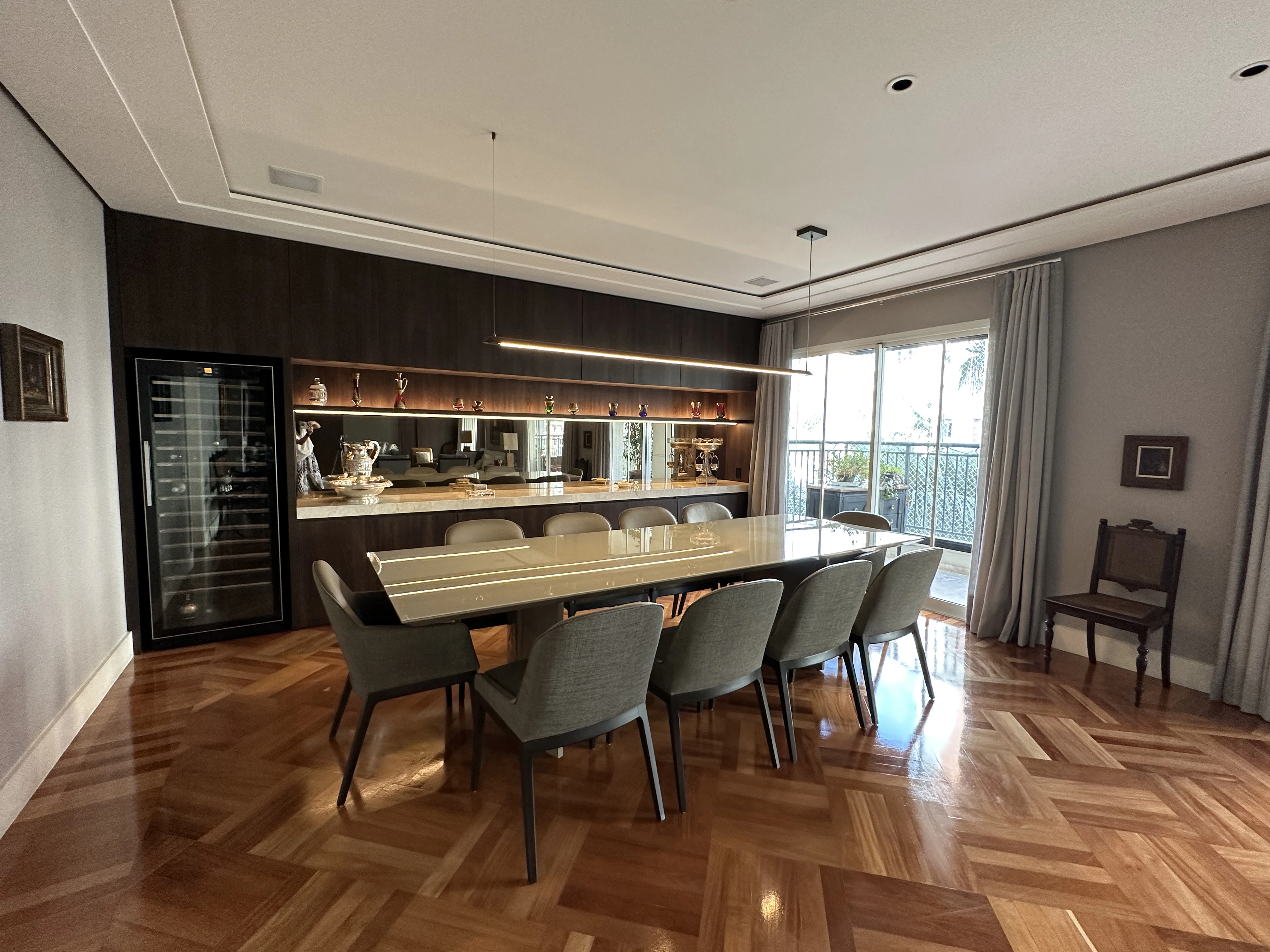 Sala de jantar de residência projetada por Denise Kaupert, com mesa para dez lugares, adega climatizada e piso em parquet de madeira